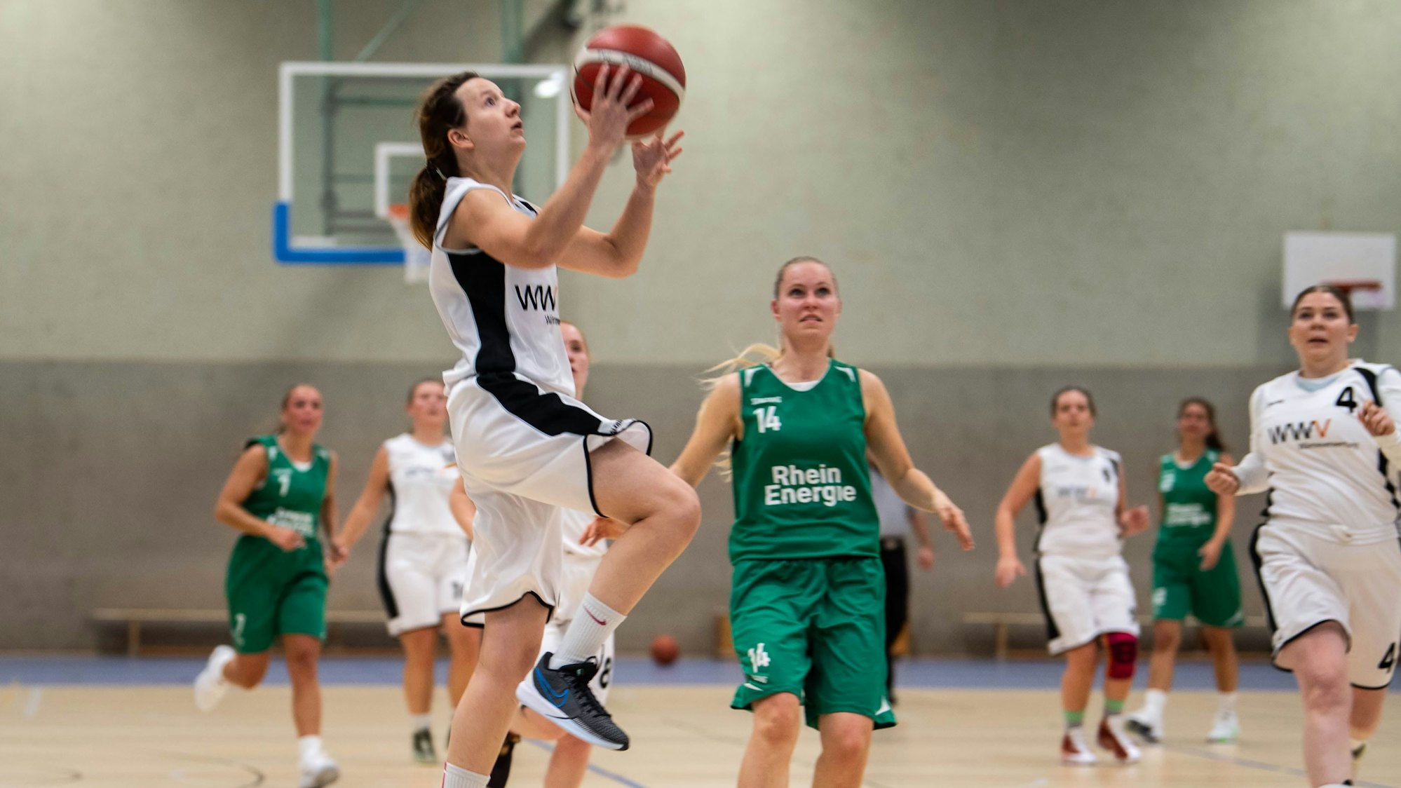 Die Zülpicherin beim Korbleger, Gegnerinnen und Mitspielerinnen schauen zu.