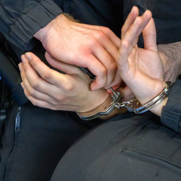 Ein Polizist legt einem Mann Handschellen an.