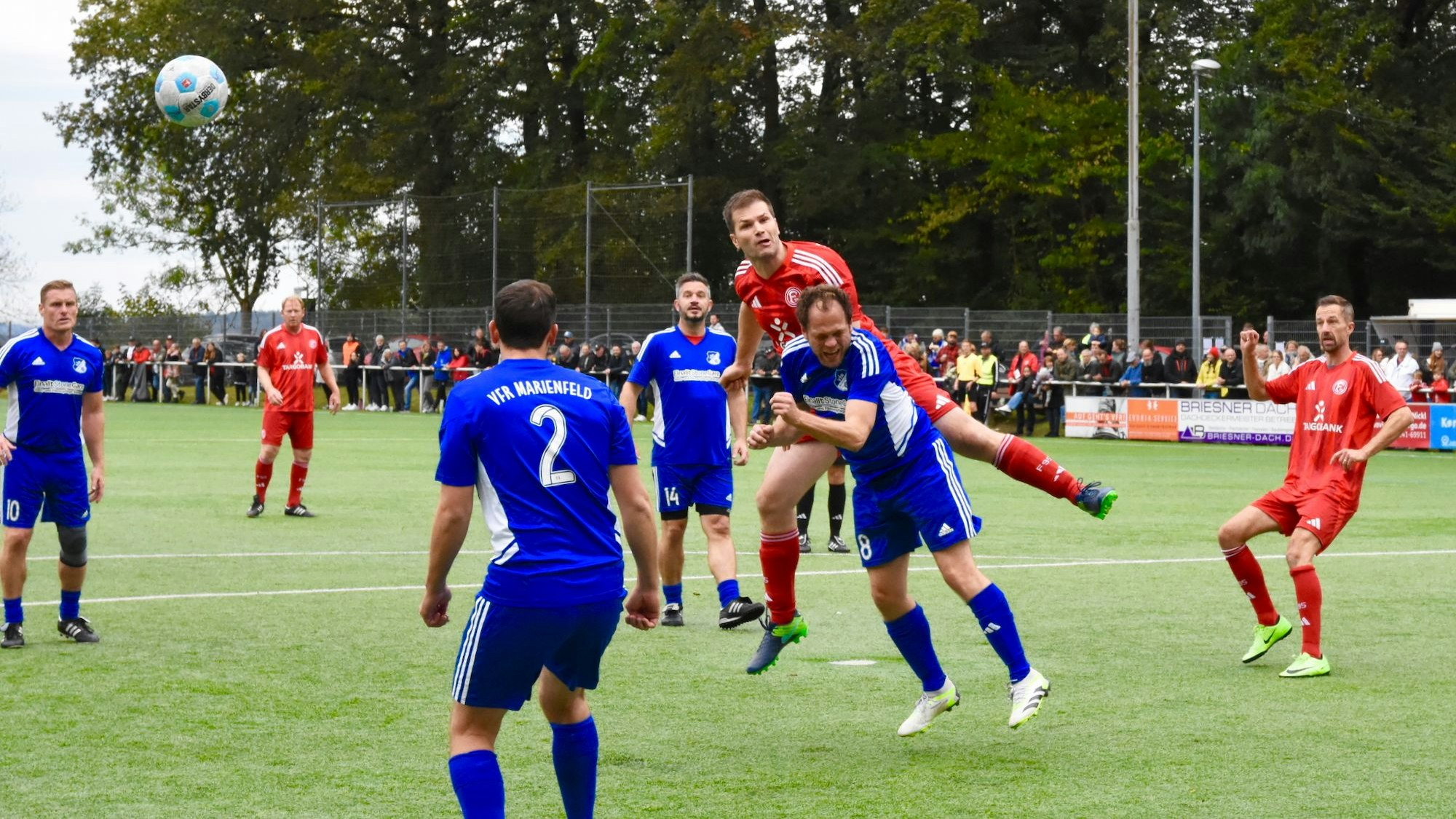 Männer in roten und blauen Trikots spielen Fußball.