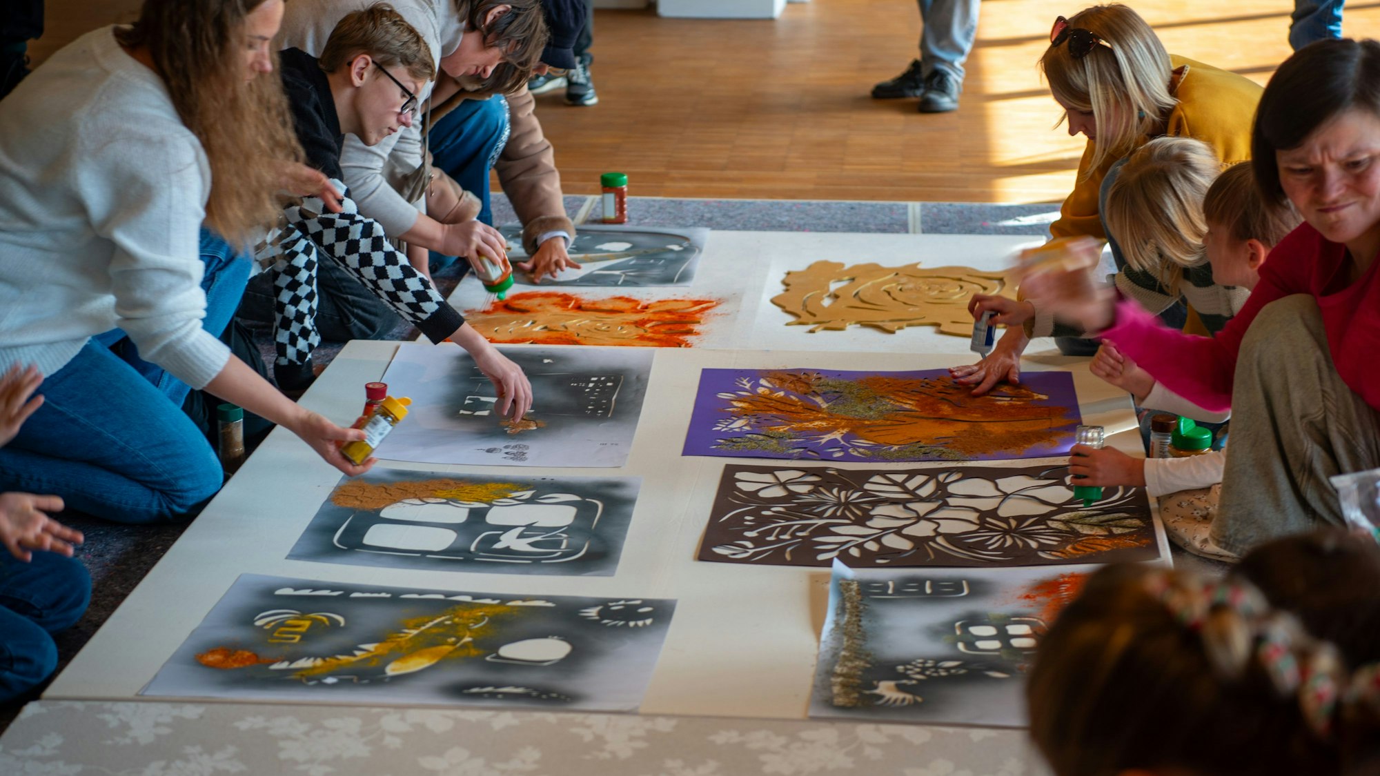 Verschiedene Menschen gestalten mit Gewürzen und Schablonen Bilder.