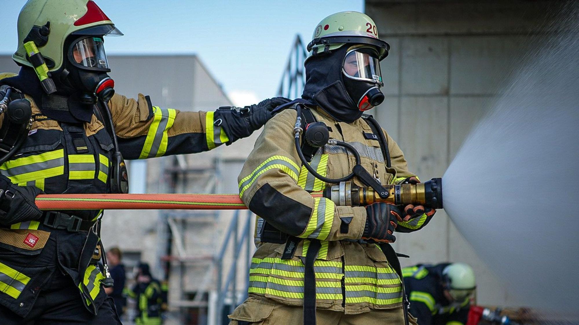 Zwei Feuerwehrfrauen bei einer Übung mit Löschwasserrohr