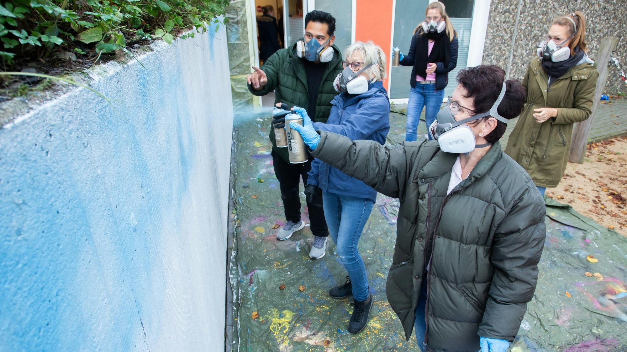 Das Foto zeigt Mitarbeiterinnen von Don Bosco und frühere Beschäftigte, die  Graffiti zum Geburtstag der Kita sprayen.
