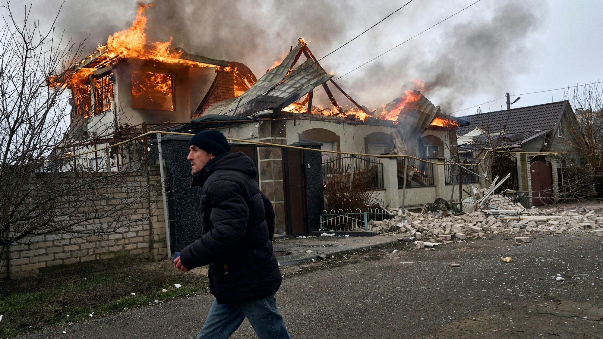 Ein Anwohner läuft an einem brennenden Haus in Cherson vorbei, das nach ukrainischen Angaben bei russischem Beschuss getroffen wurde. (Archivbild)