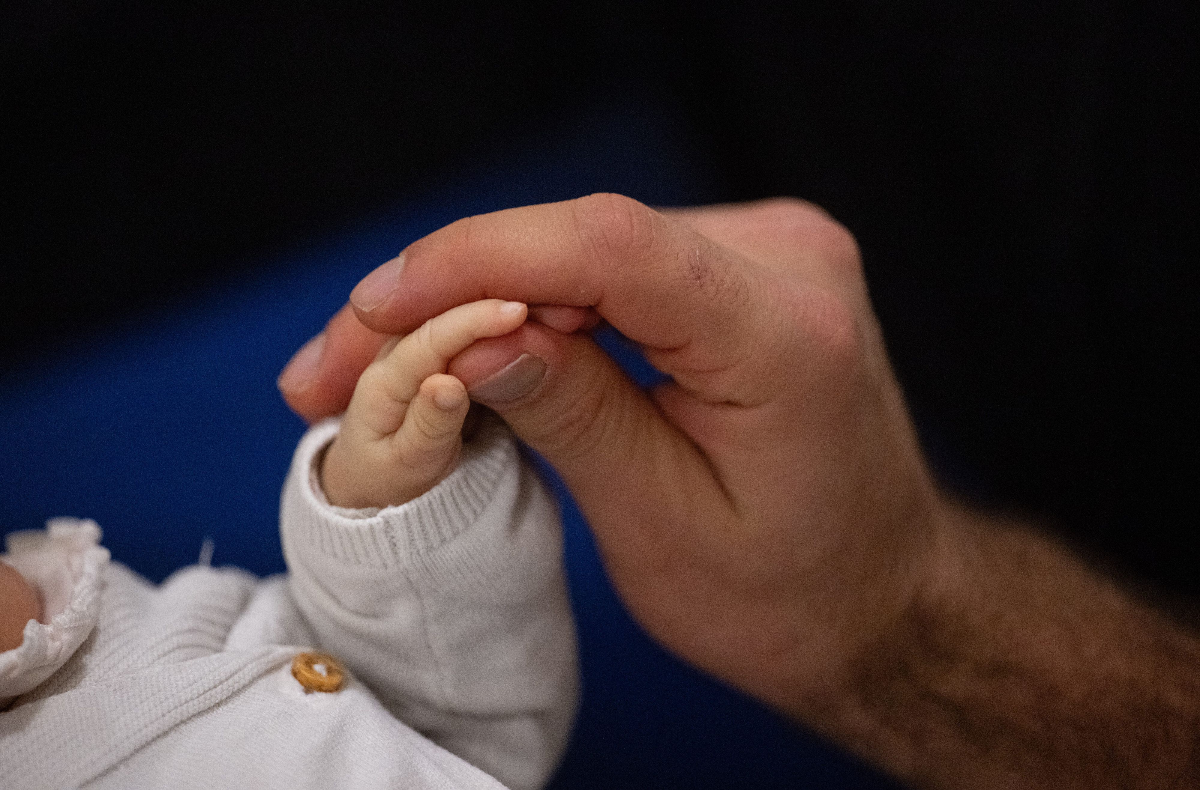 Ein Vater berührt während eines Infant Handling Kurses die Hand seines Kindes.