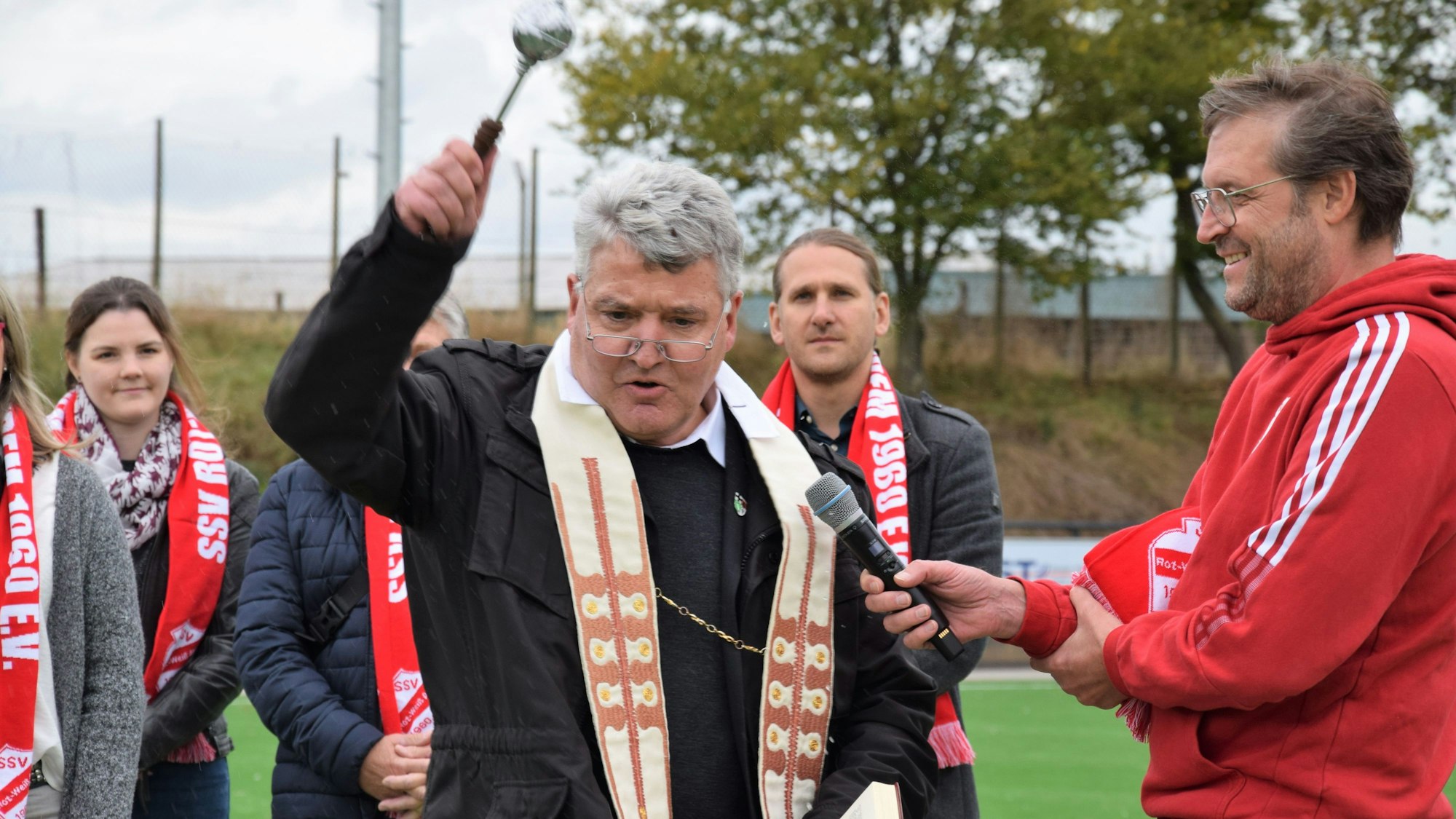 Ein Pfarrer segnet einen Fußballplatz.