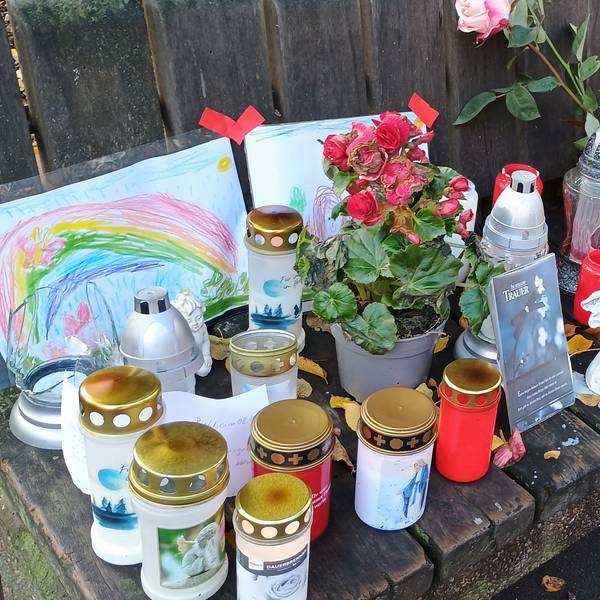 Auf einer Bank haben Pulheimer Anwohner Kerzen, Blumen, Bilder und Briefe abgelegt.