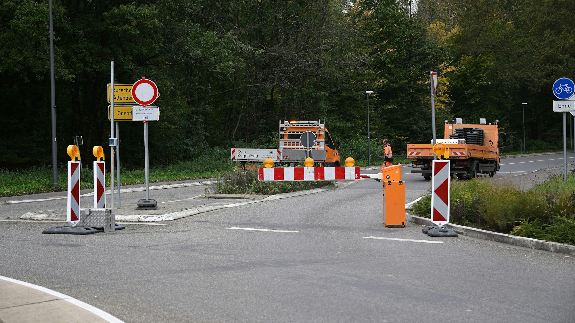 Ein Kreisverkehr, darauf Baufahrzeuge und eine Schranke.