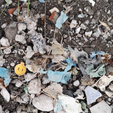 Das Bild zeigt Schotter, in dem sich Plastikreste befinden.
