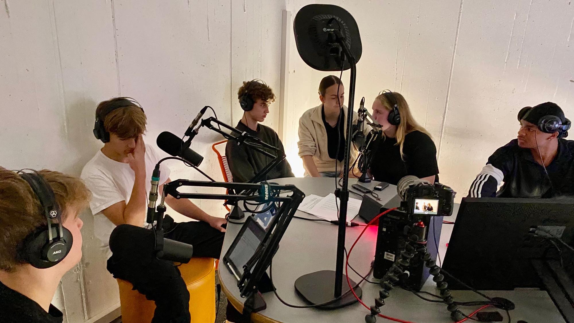 Jugendliche sitzen in einem Aufnahmestudio.