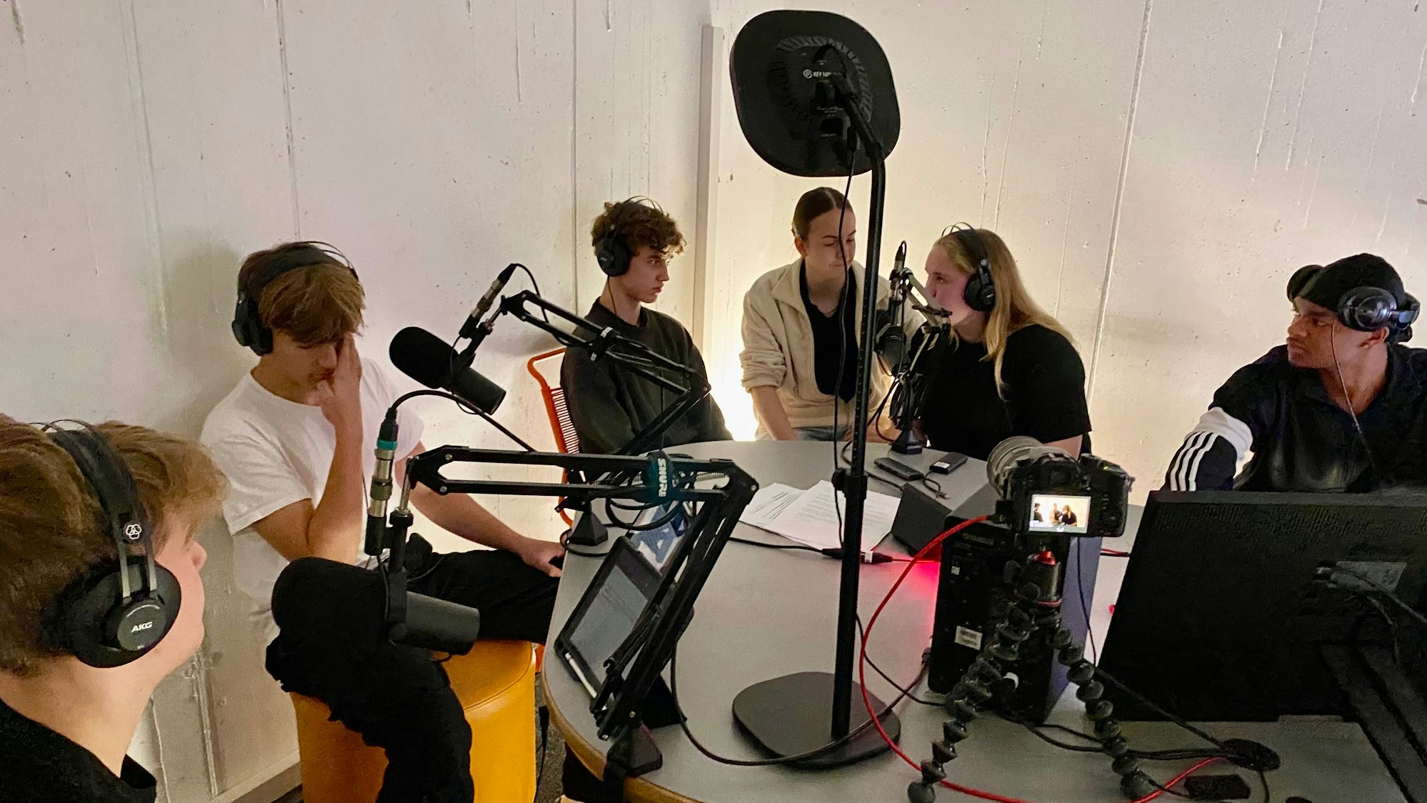Jugendliche sitzen in einem Aufnahmestudio.