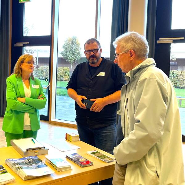 Drei Menschen stehen an einem Tisch mit Informationsbroschüren der Steb.