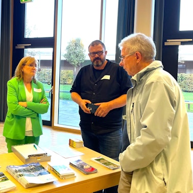 Drei Menschen stehen an einem Tisch mit Informationsbroschüren der Steb.