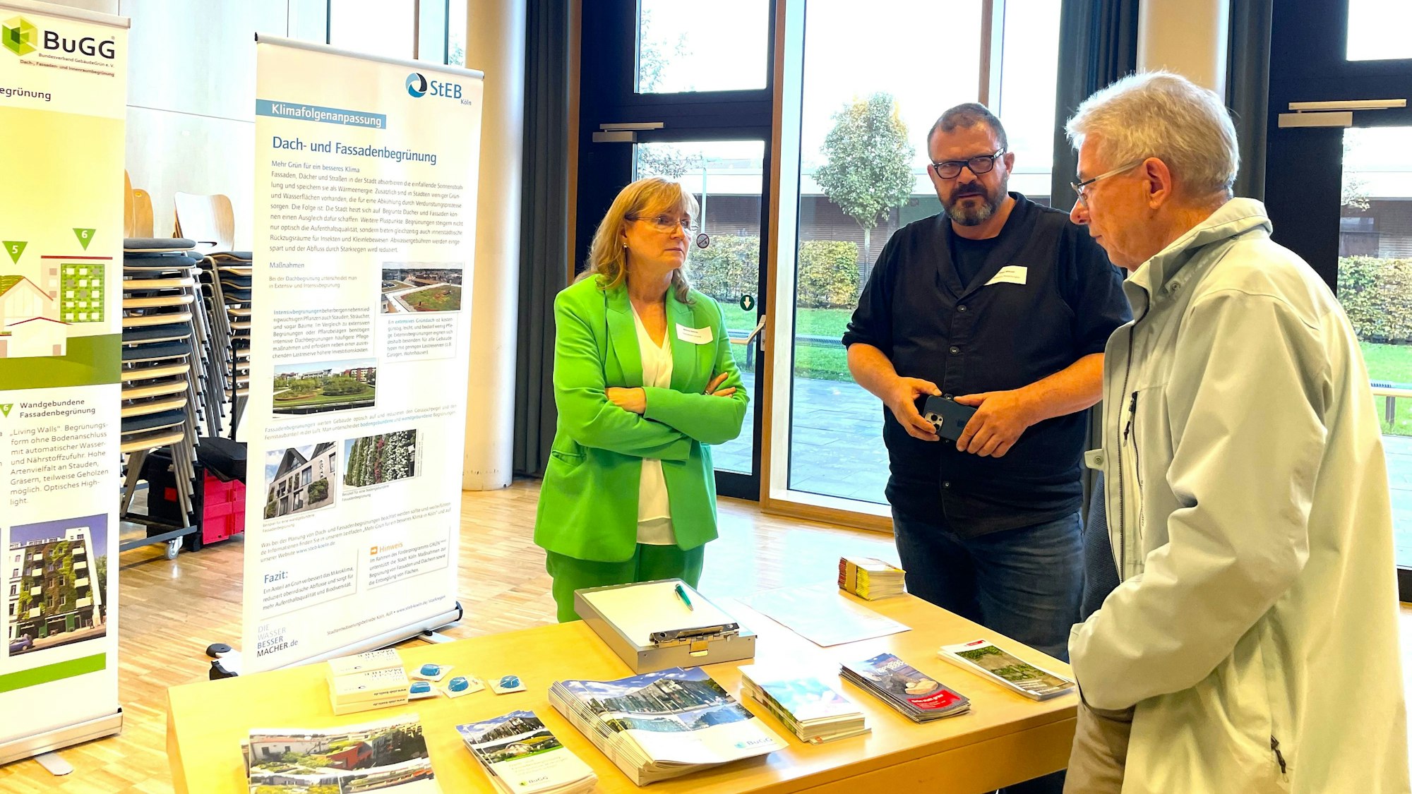 Drei Menschen stehen an einem Tisch mit Informationsbroschüren der Steb.