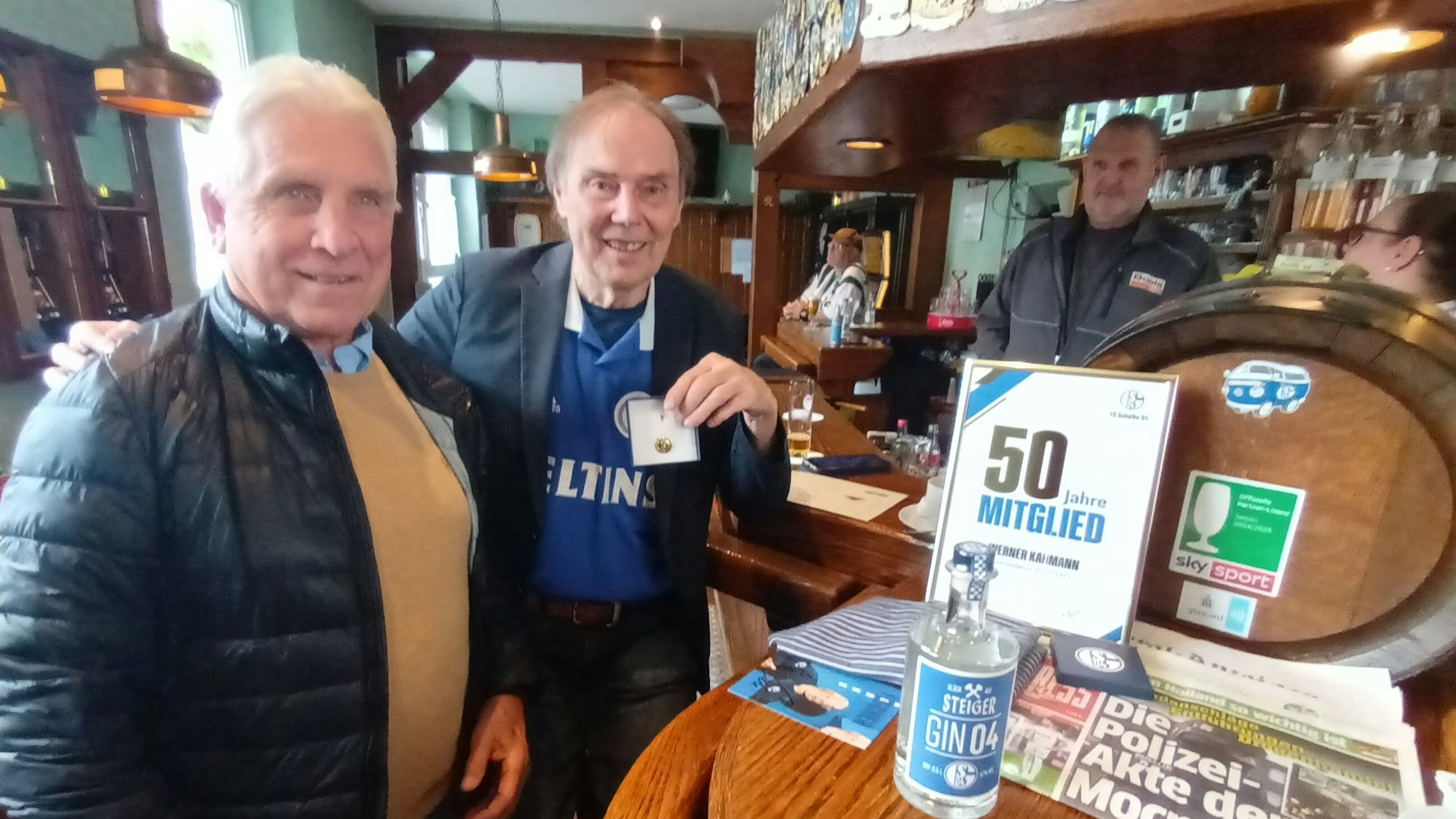 Zwei Männer stehen am Tresen in einer Kneipe.