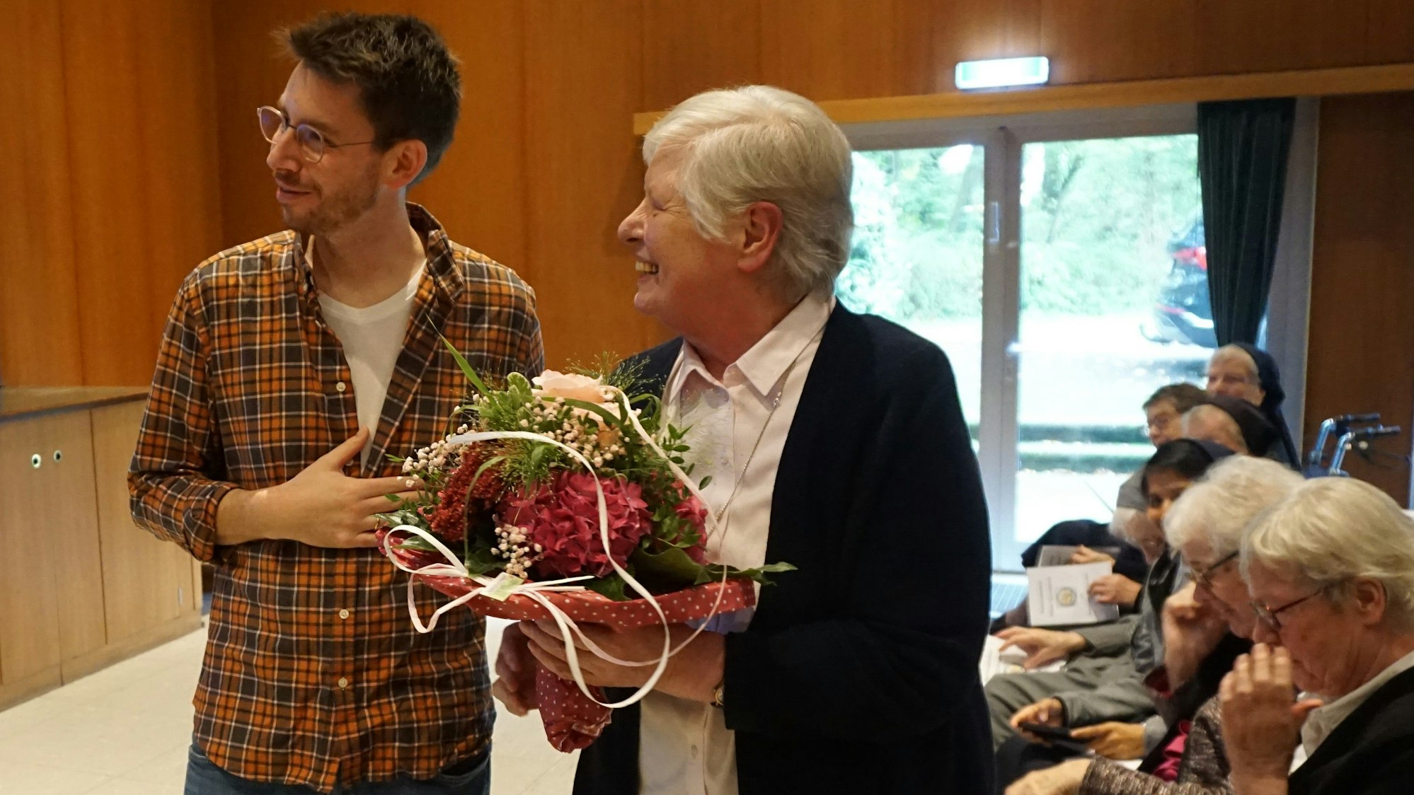 Das Bild zeigt einen Mann und eine Frau mit einem Blumenstrauß in der Hand.