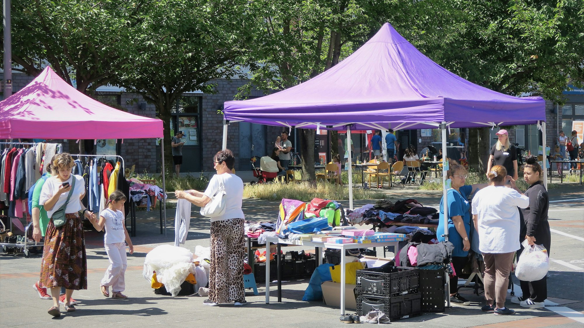 Das Foto zeigt einen Stand mit Kleidung und mehrere Personen.
