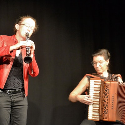 Links steht Susi Evans und spielt Klarinette, rechts sitzt Szilvia Csaranko mit ihrem Akkordeon.