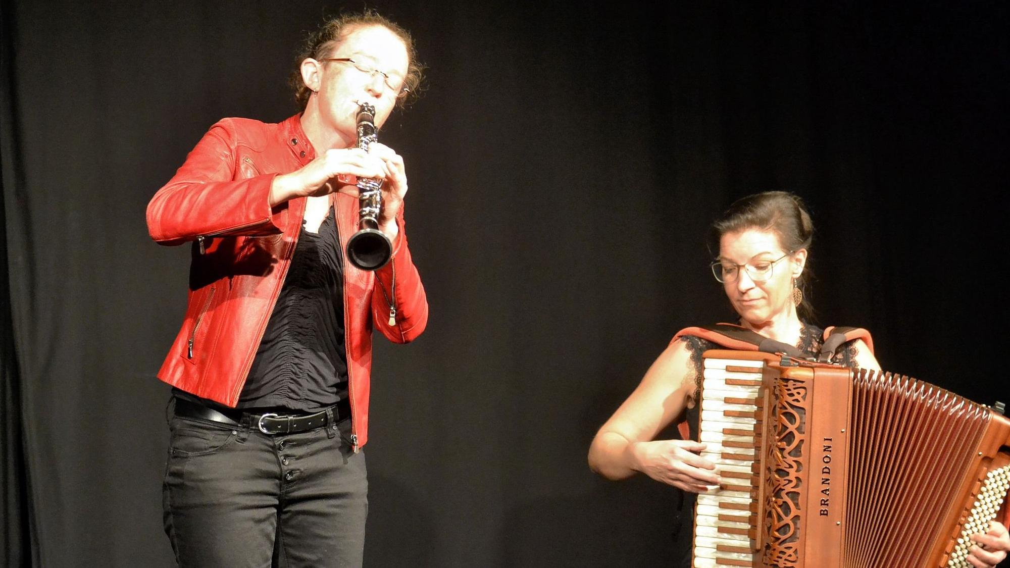 Links steht Susi Evans und spielt Klarinette, rechts sitzt Szilvia Csaranko mit ihrem Akkordeon.