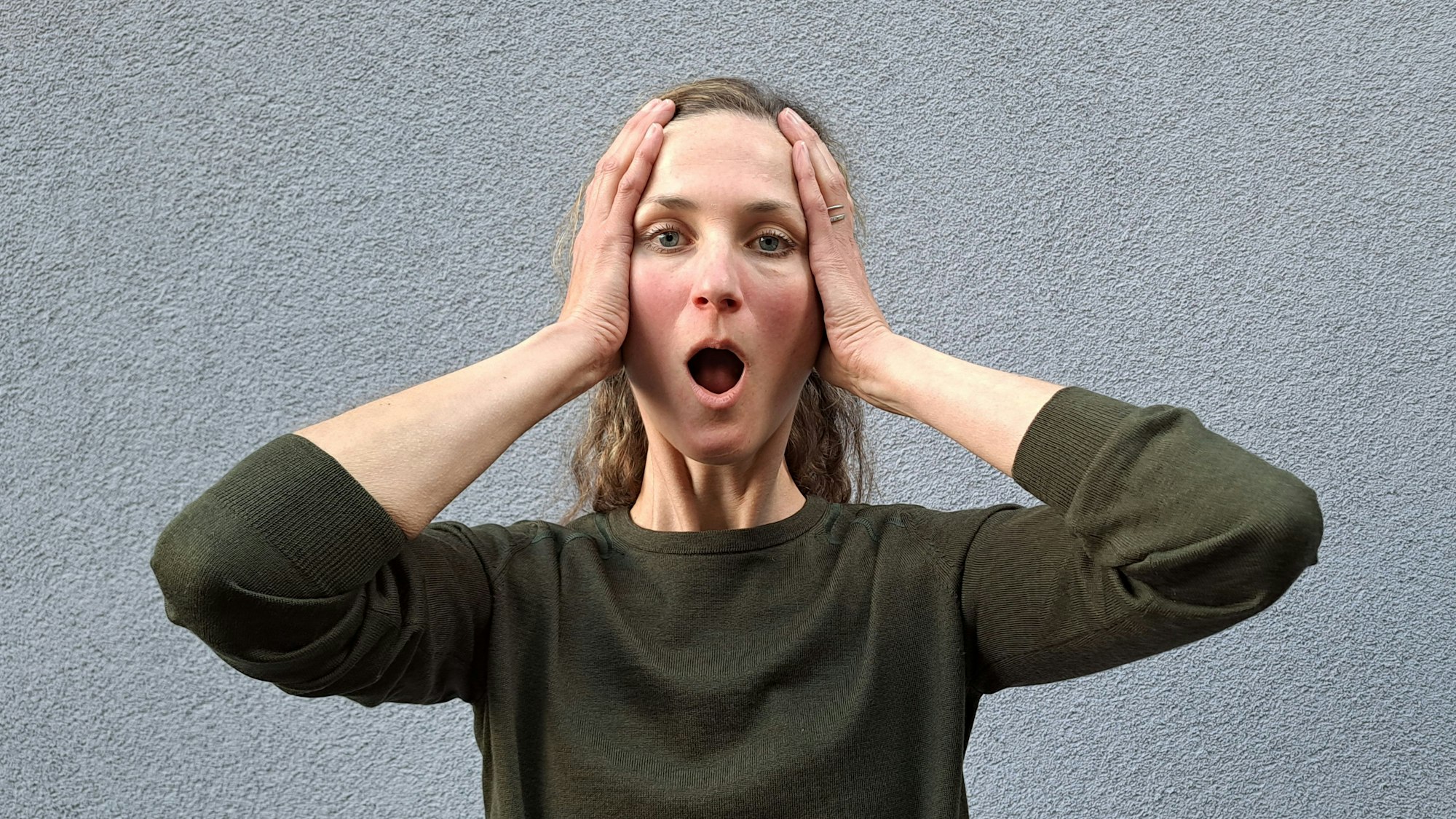 Laura Hegemann zeigt mit weit geöffnetem Mund die Face-Yoga-Übung „Big O“.