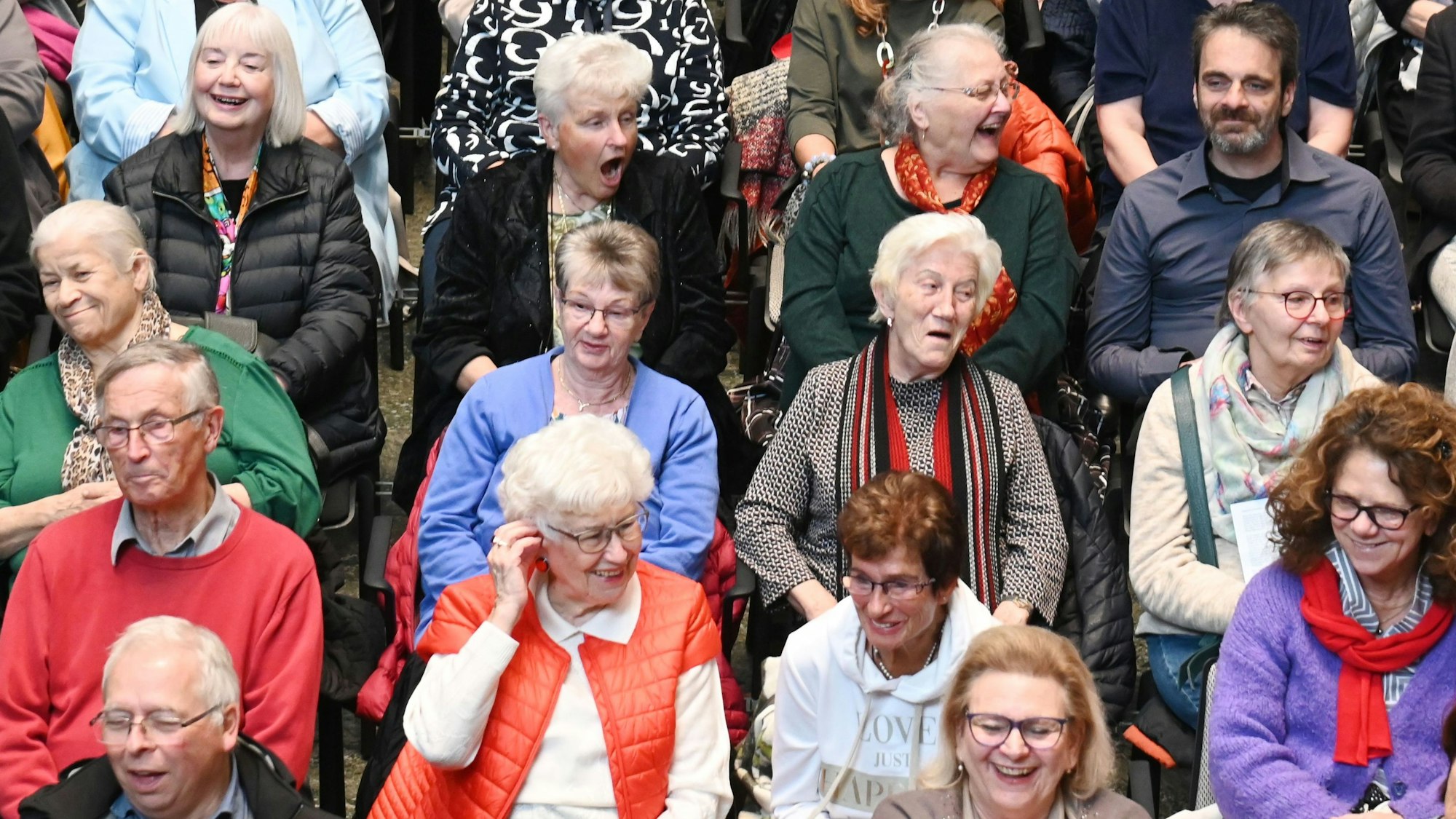 Zu sehen sind mehrere Menschen, die neben- und hintereinander sitzen.