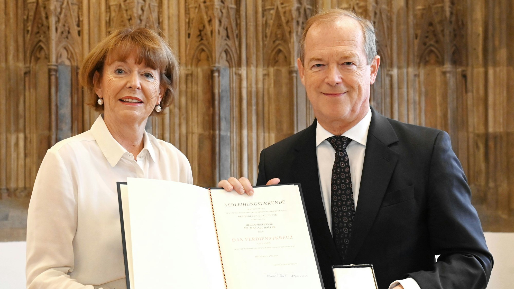 Zu sehen sind Oberbürgermeisterin Henriette Reker und Professor Dr. Michael Hallek, die eine Urkunde halten.