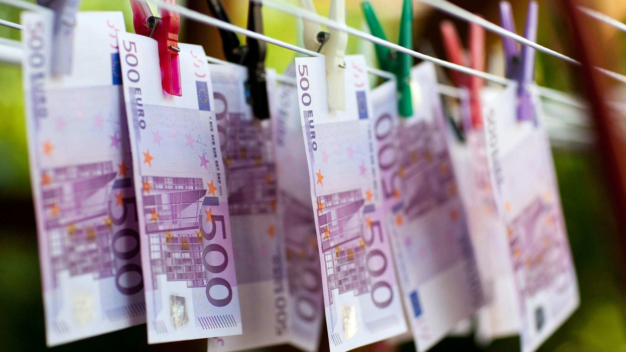 An einem Wäscheständer hängen mit Klammern befestigt Geldscheine