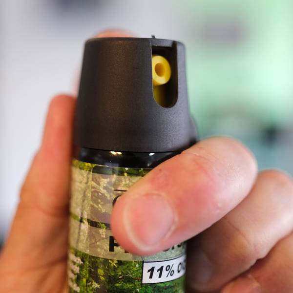 Eine Hand hält eine Kartusche mit Pfefferspray.