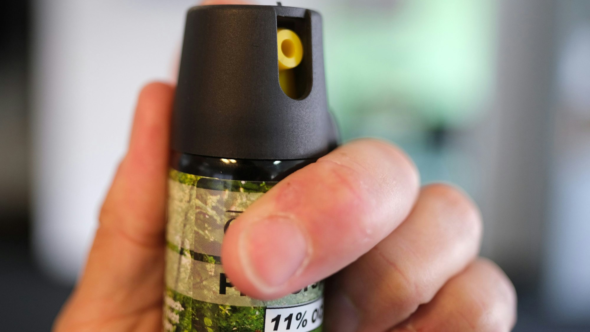 Eine Hand hält eine Kartusche mit Pfefferspray.