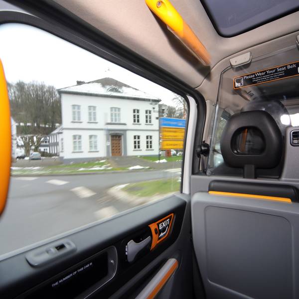 Durch das Fenster eines Sammeltaxis schaut man auf das Odenthaler Rathaus im Winter.