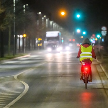 Eine Frau fährt am frühen Morgen mit einem Fahrrad über eine Straße