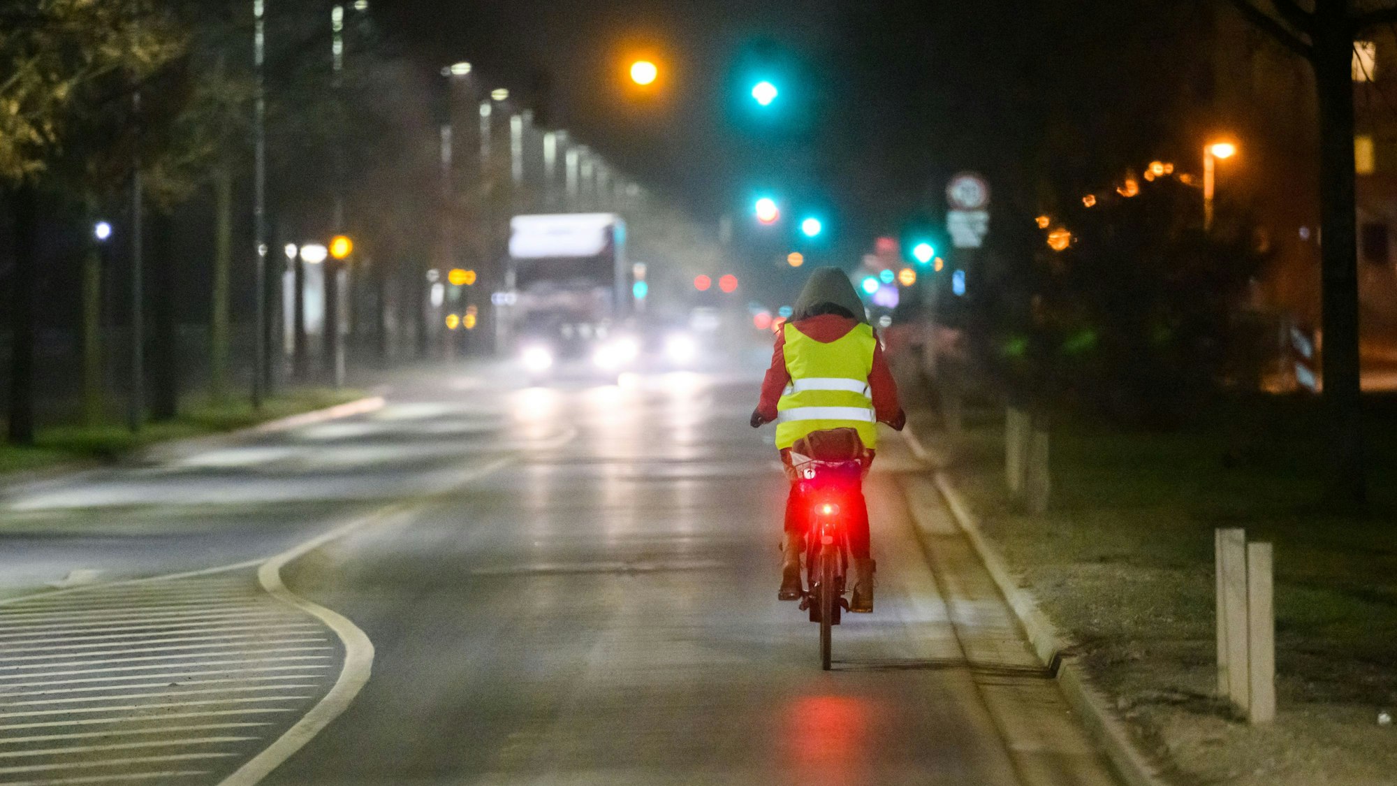 Eine Frau fährt am frühen Morgen mit einem Fahrrad über eine Straße