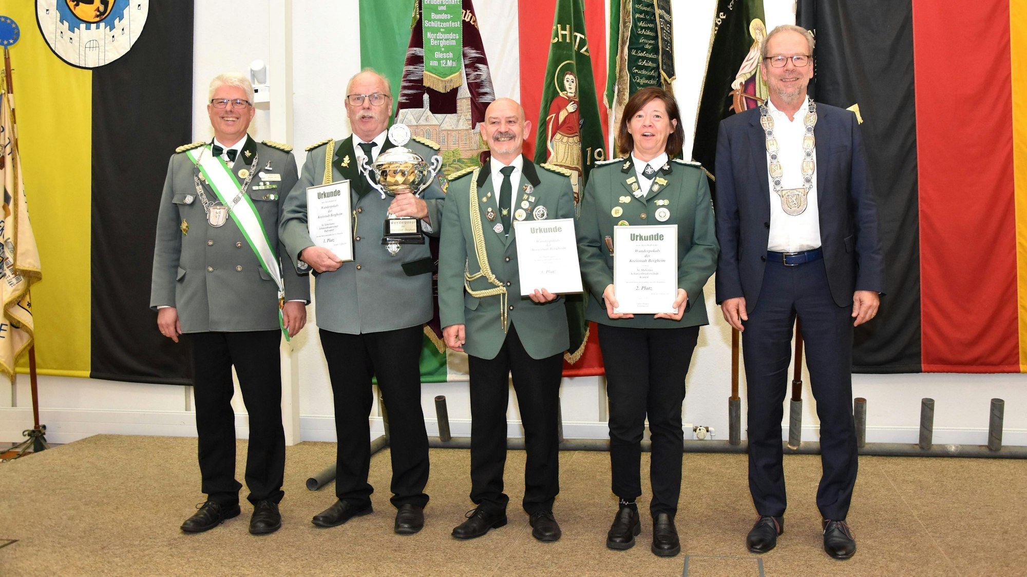 Die in Grün gekleideten Schützen halten ihre Urkunden, einer hält den Pokal.