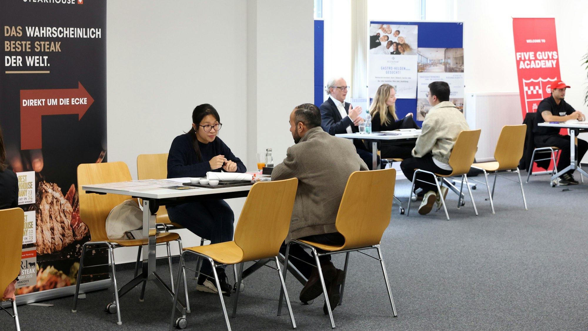 Teilnehmer der Bewerbungsmesse „BeMega“ sitzen an Tischen in der Agentur für Arbeit
