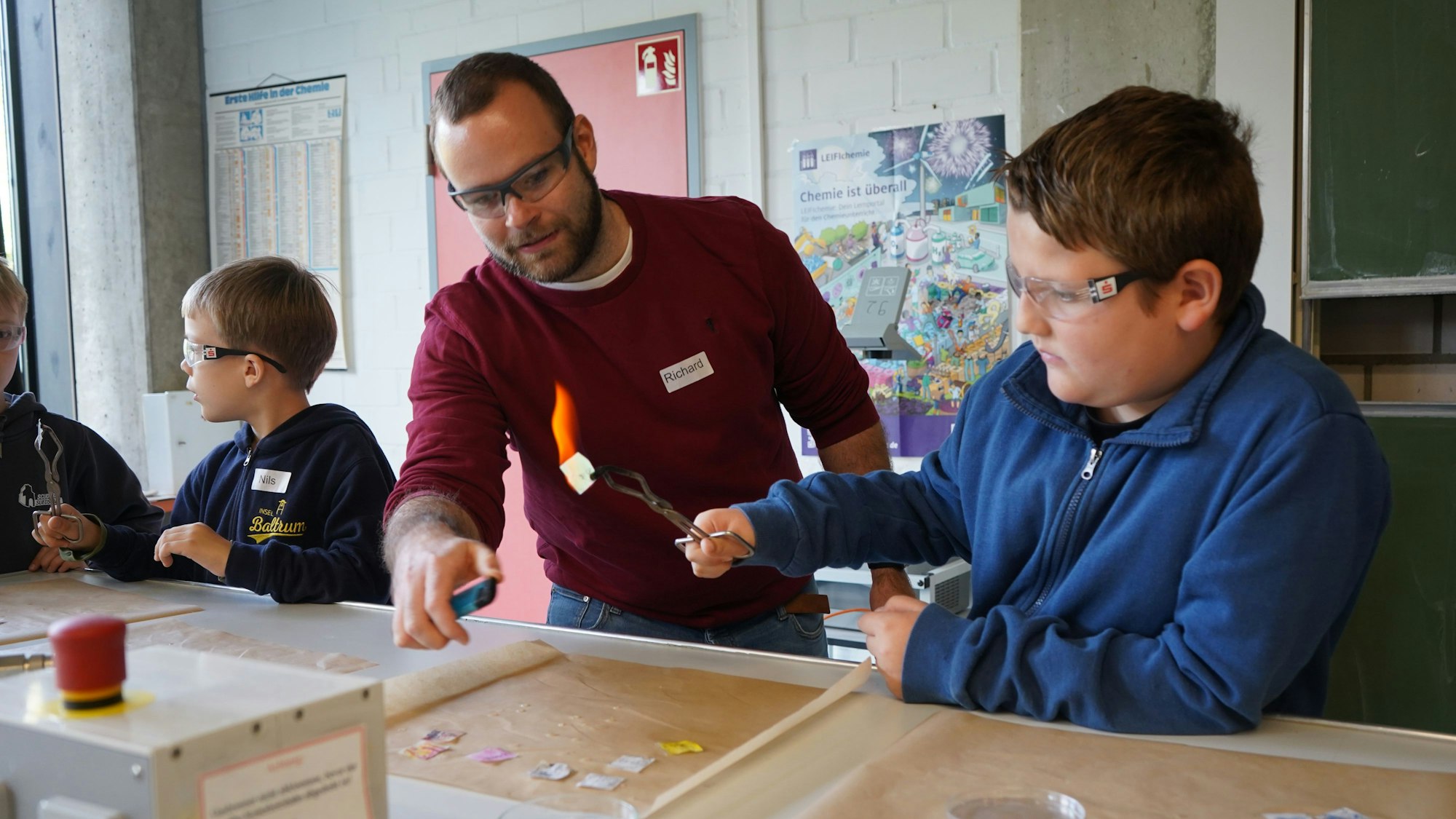 Das Bild zeigt einen Lehrer und einen Jungen bei einem chemischen Experiment mit Feuer.