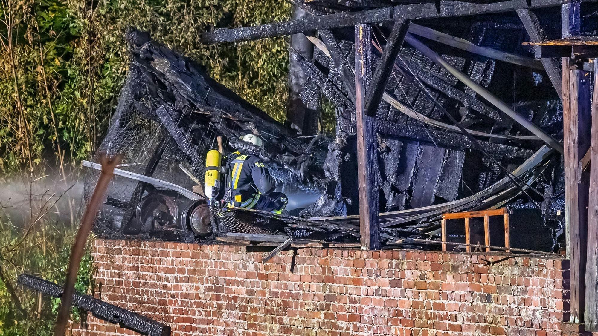 Ein Feuerwehrmann mit Atemschutz vor einem ausgebrannten Gebäude.