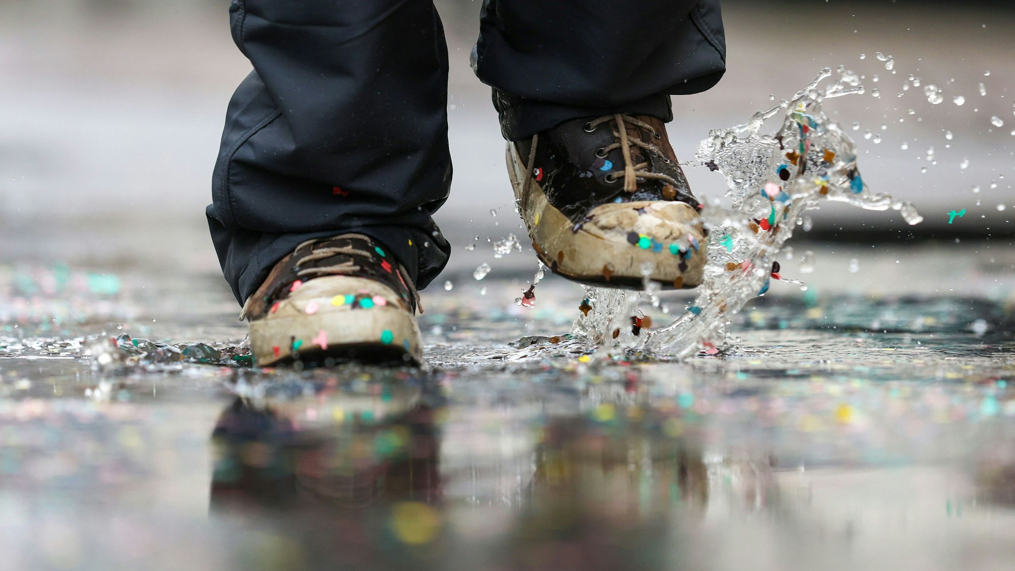 Eine Pfütze mit Konfetti: Die Regenwolken, die zum Wochenstart auch Köln erreichen werden, könnten sich rechtzeitig zum Start des Straßenkarnevals wieder verziehen.