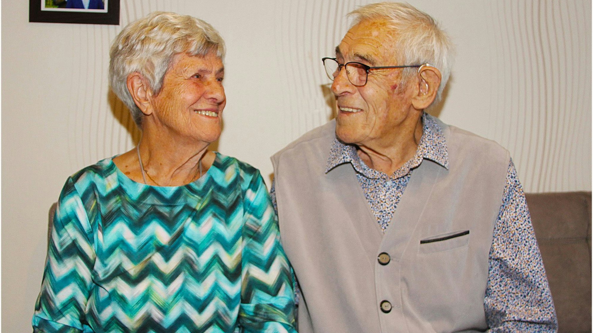 Maria und Klaus Esser sitzen auf einer Bank und schauen sich lächelnd an. Sie sind seit 65 Jahren miteinander verheiratet.