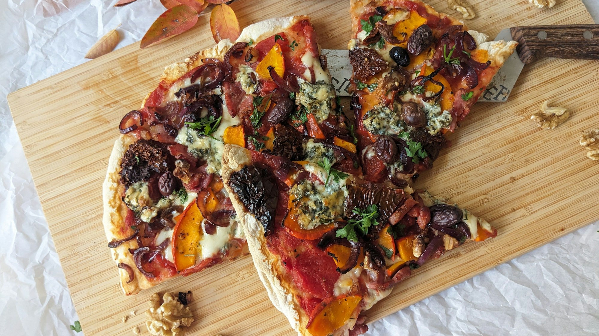 Eine in Stücke geschnittene Pizza liegt auf einem Holzbrett.