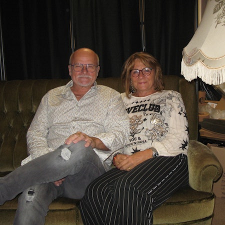 Ingo und Gaby Teusch sitzen auf dem Hennefer Sofa, rechts daneben steht eine altmodische Stehlampe.