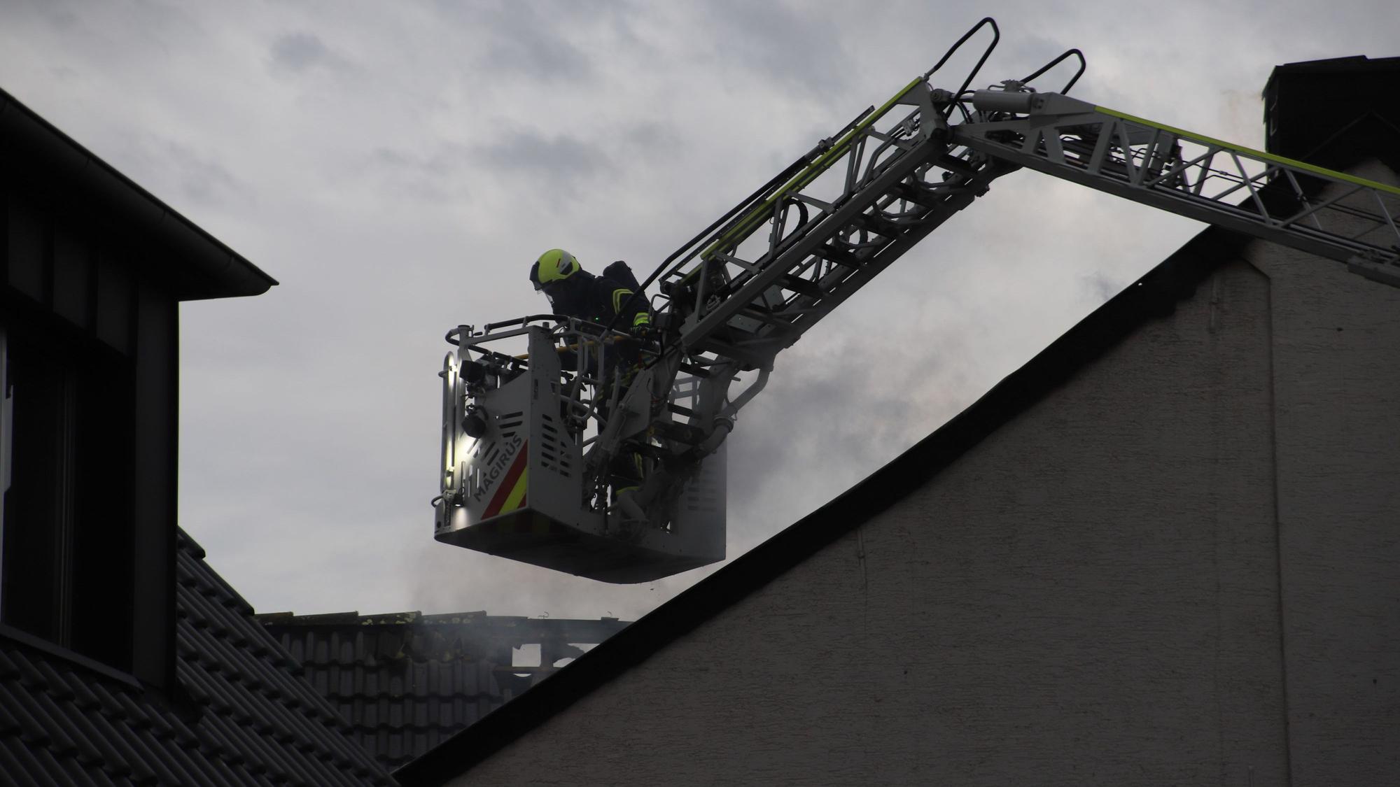 Ein Feuerwehrmann im Korb einer Drehleiter bekämpft einen Brand.