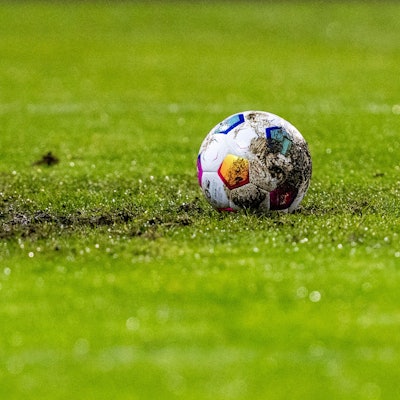 Ein Fußball liegt am Elfmeterpunkt im matschigen Rasen.
