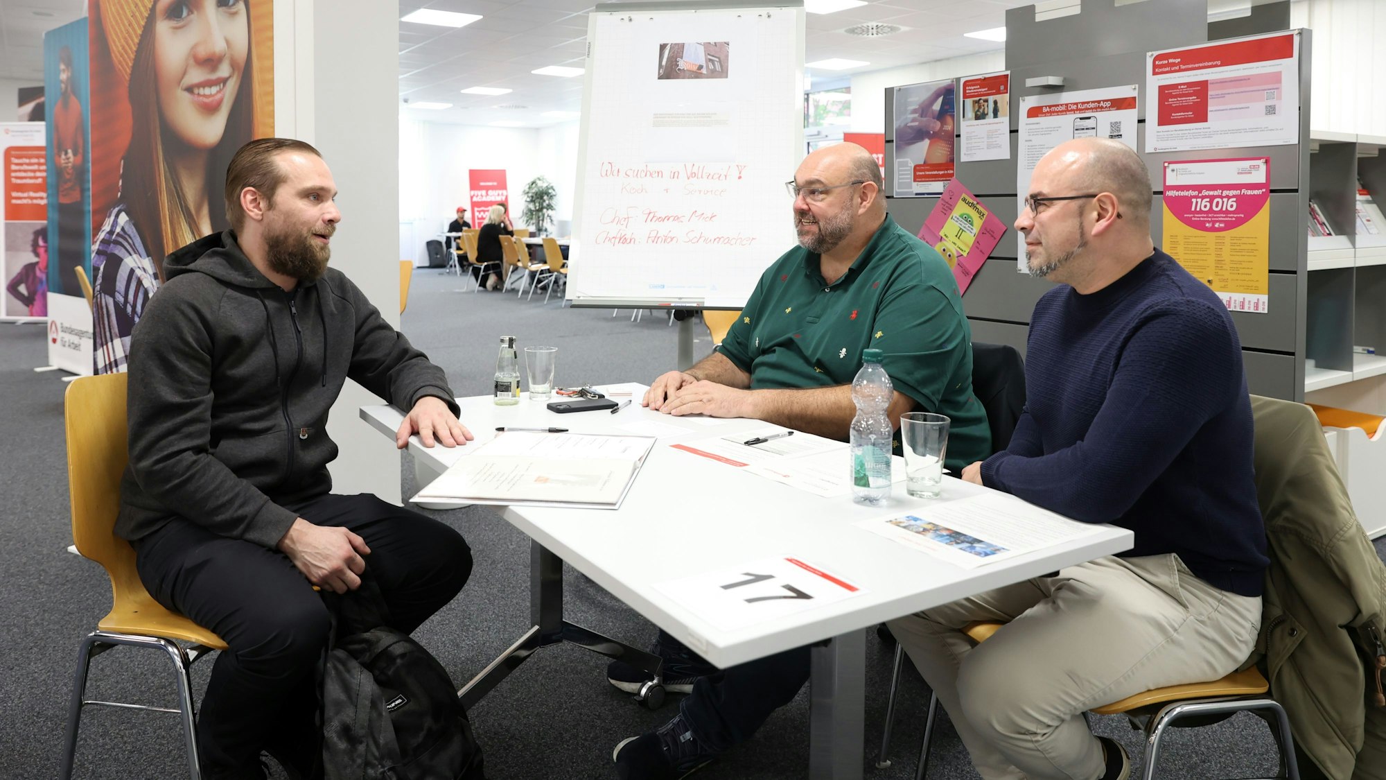 Konstantin Boos, Thomas Mick und Anton Schumacher
sitzen an einem Tisch in der Arbeitsagentur Köln