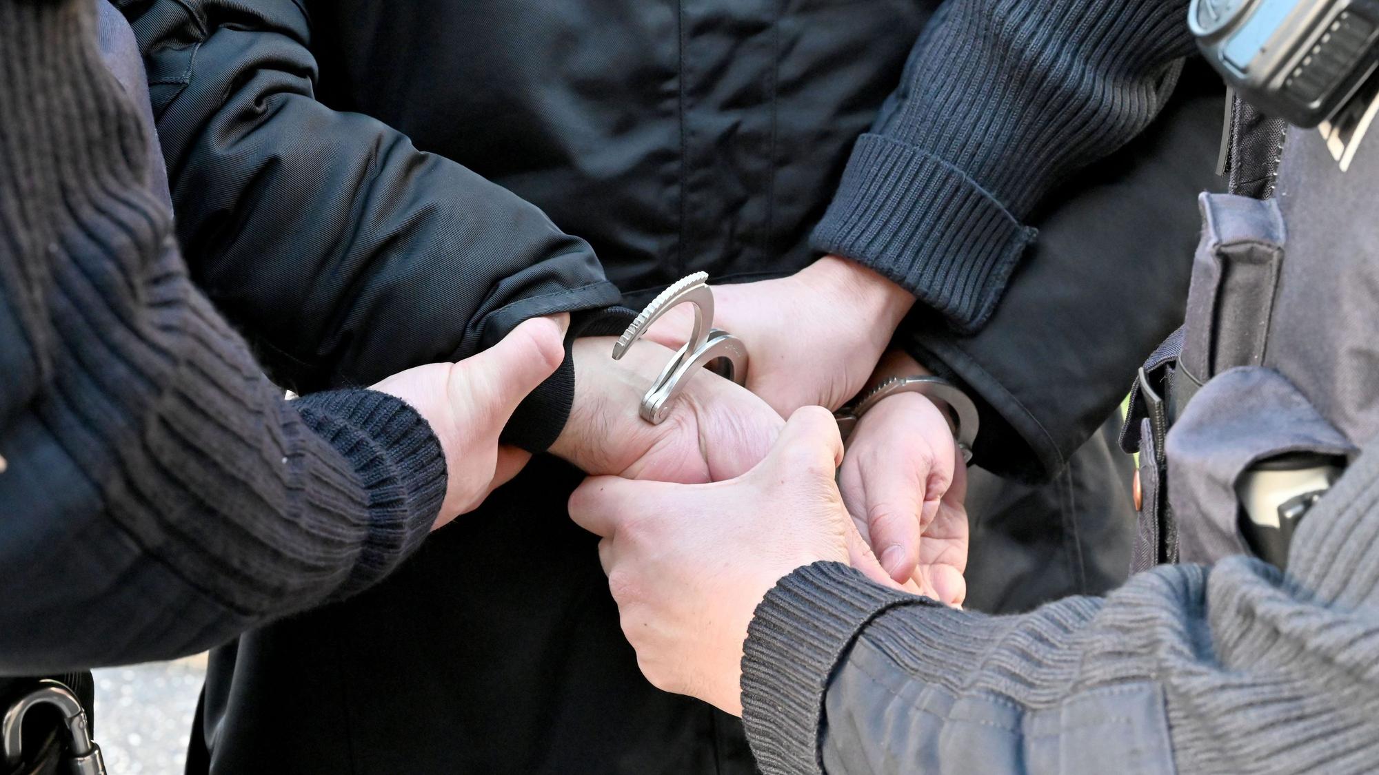 Polizisten legen einem Mann Handschellen an