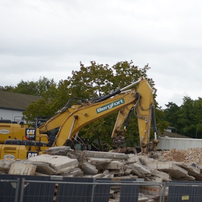 Mit einem Bagger werden die Überreste eines Gebäudes des Berufskollegs bewegt.