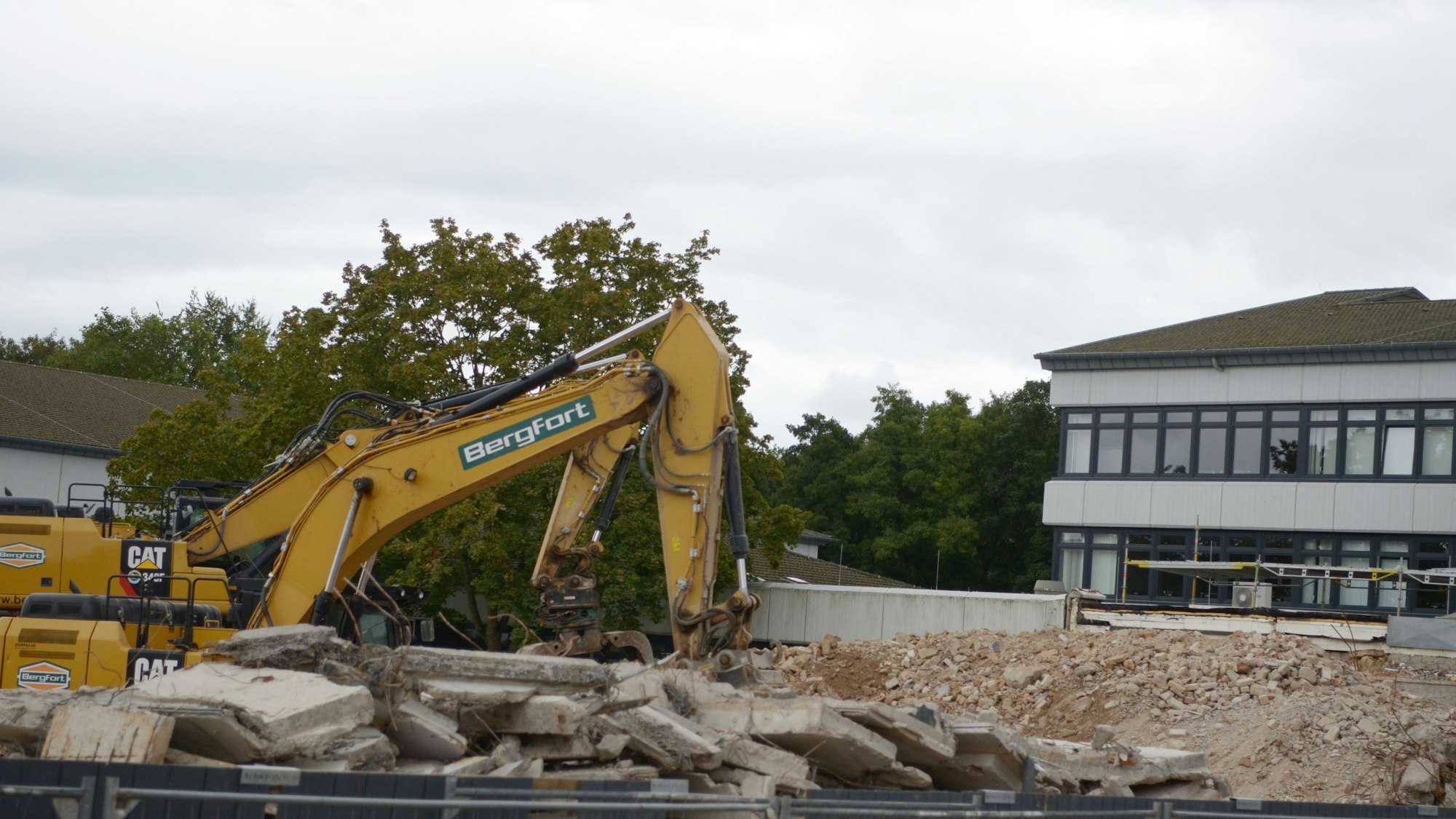 Mit einem Bagger werden die Überreste eines Gebäudes des Berufskollegs bewegt.