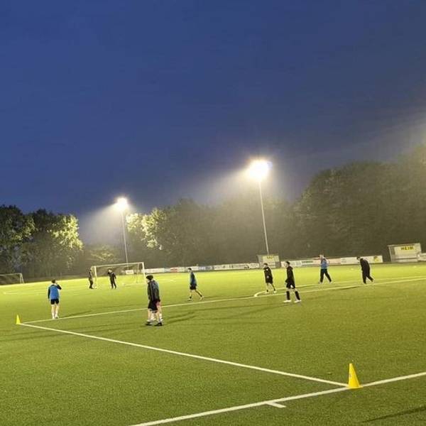 Auf dem Bild ist der beleuchtete Platz zu sehen, einige Kinder spielen Fußball.