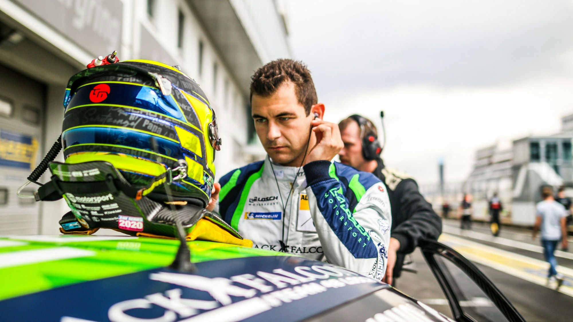 Der Rennfahrer steht an seinem Auto, sein Helm liegt auf dem Dach.