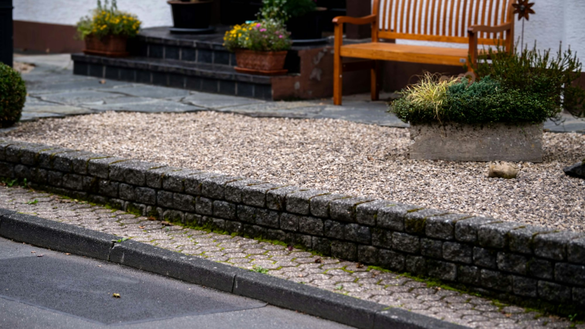 Das Bild zeigt einen Vorgarten im Kreis Euskirchen. Zu erkennen sind ein Schottergarten mit sehr wenig Grün und eine Bank im Hintergrund.