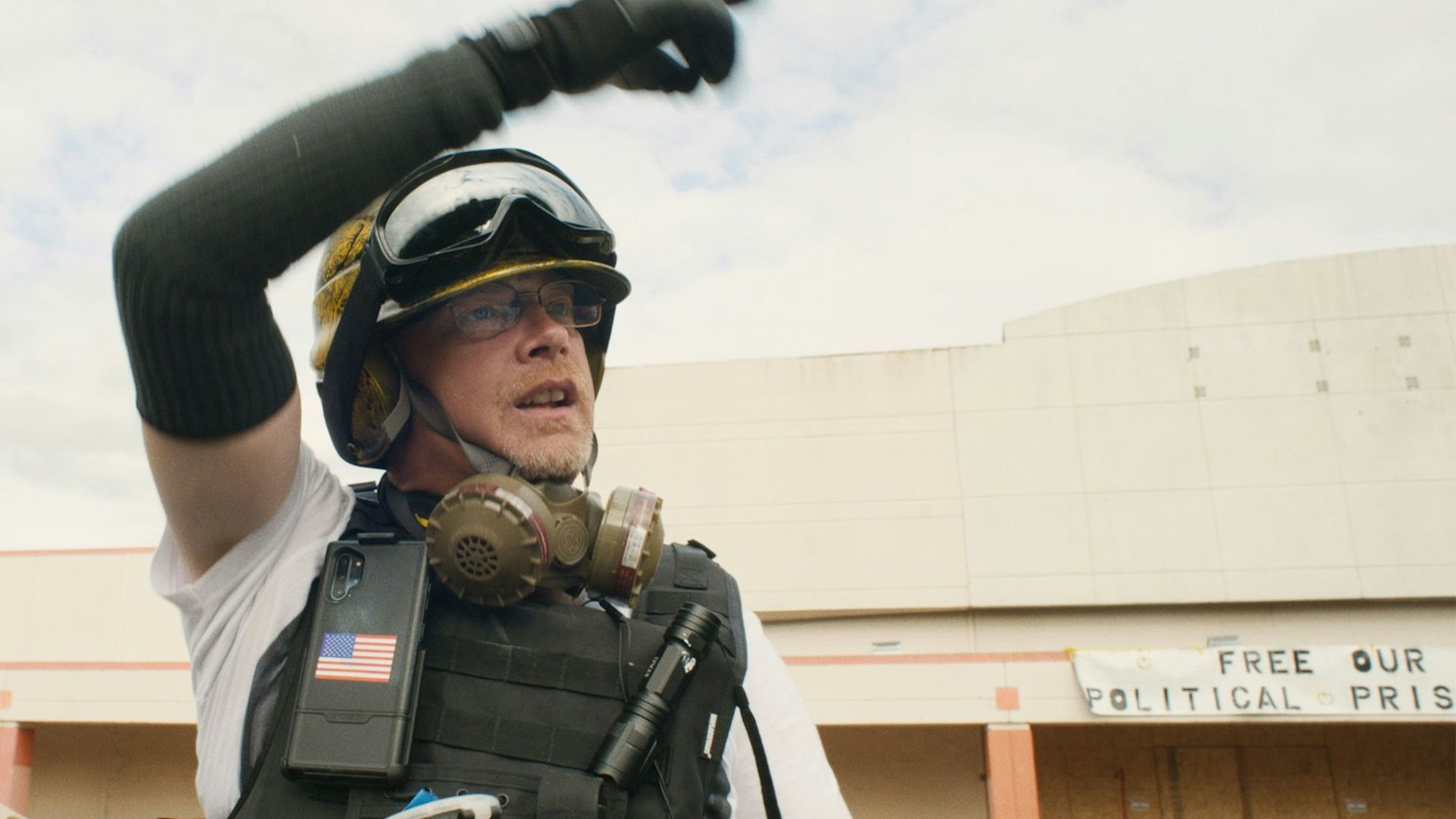 Ein Mann mit paramilitärischer Ausrüstung winkt zum Aufbruch.