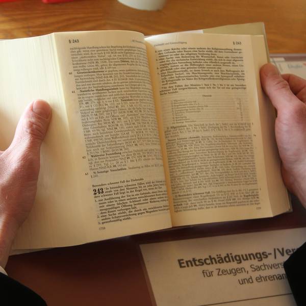 Zwei Hände halten ein aufgeschlagenes Gesetzbuch.